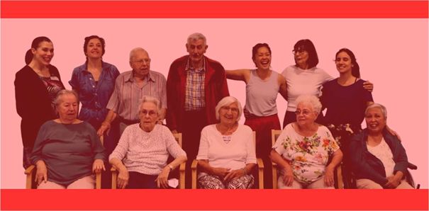 Sieben Bewohner (fünf sitzend in Holzstühlen in der vorderen Reihe und zwei stehend hinten) und fünf Mitglieder der Tanzgruppe (stehend in der hinteren Reihe) lächeln in die Kamera.